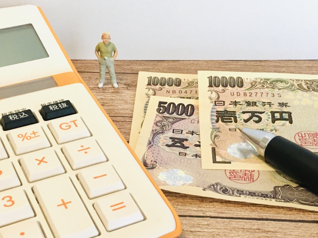 電卓と一万円札・五千円札の上に立つミニチュア人形の写真